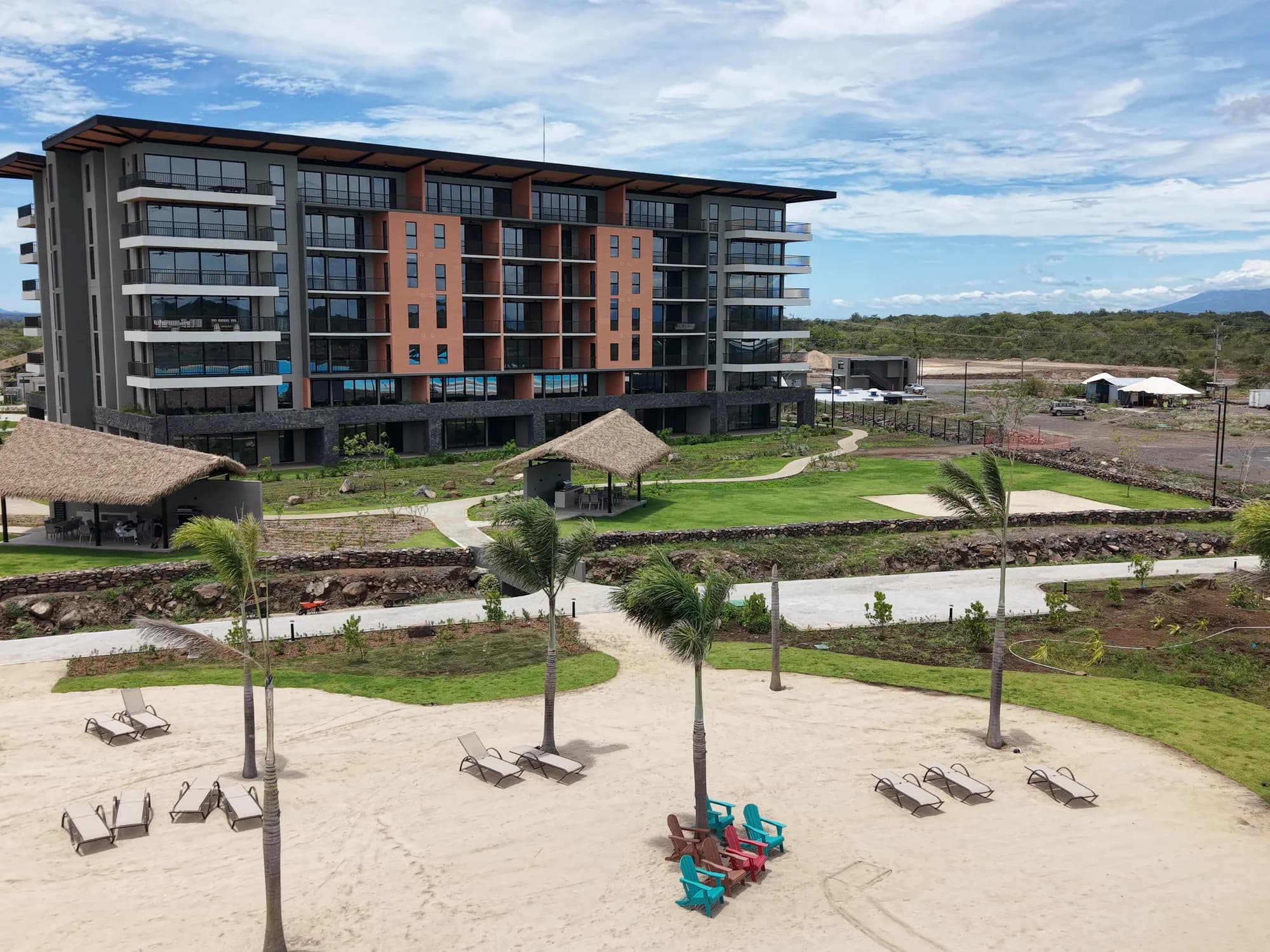 Club de playa: palapa, palmeras y camastros junto a la laguna