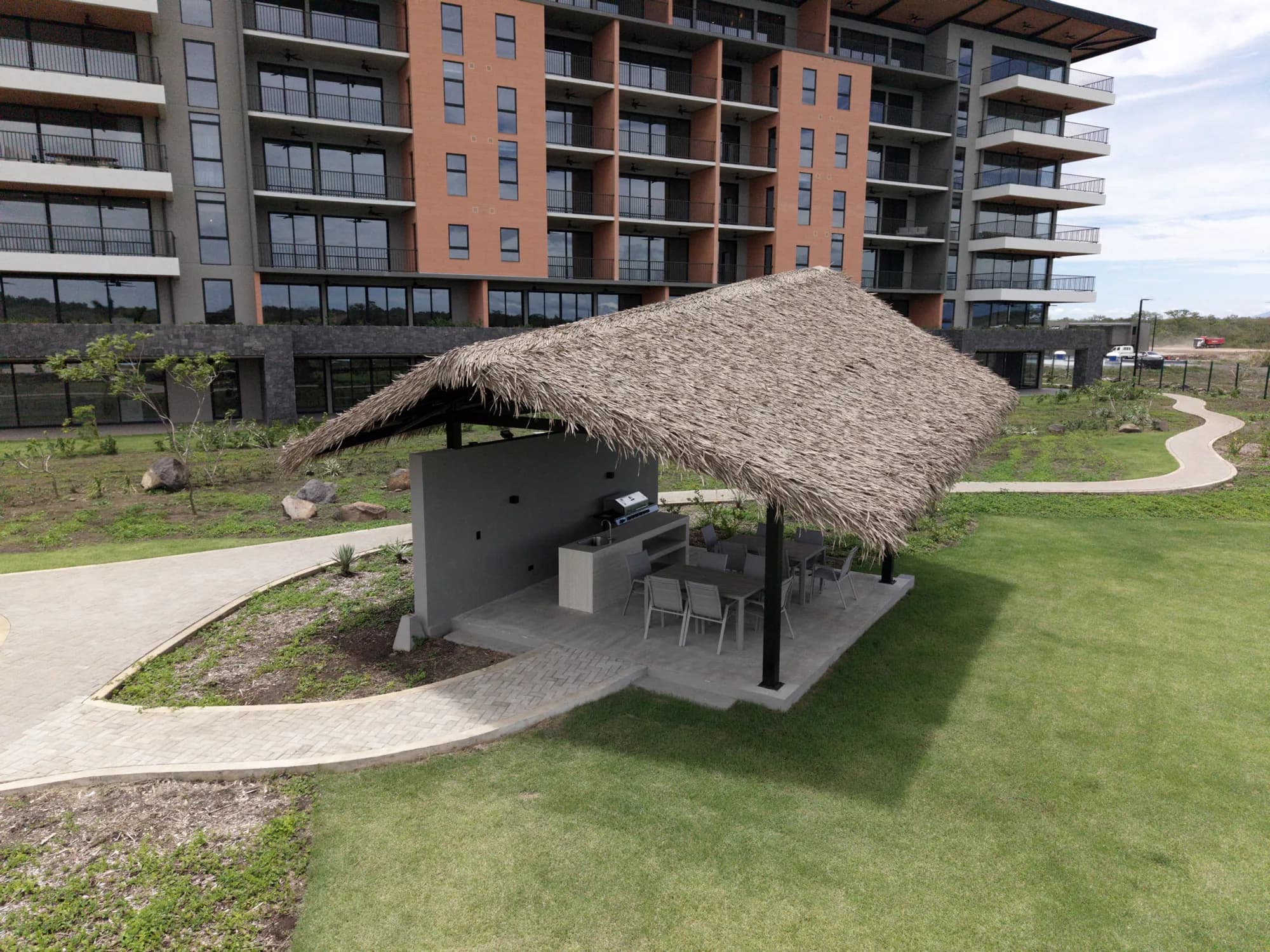 Palapa de palma sintética al pie de una torre residencial