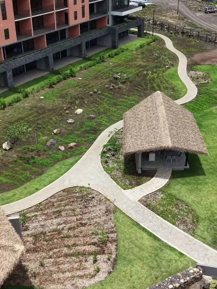 Vista aérea de una palapa de palma sintética junto a una torre residencial, Guanacaste